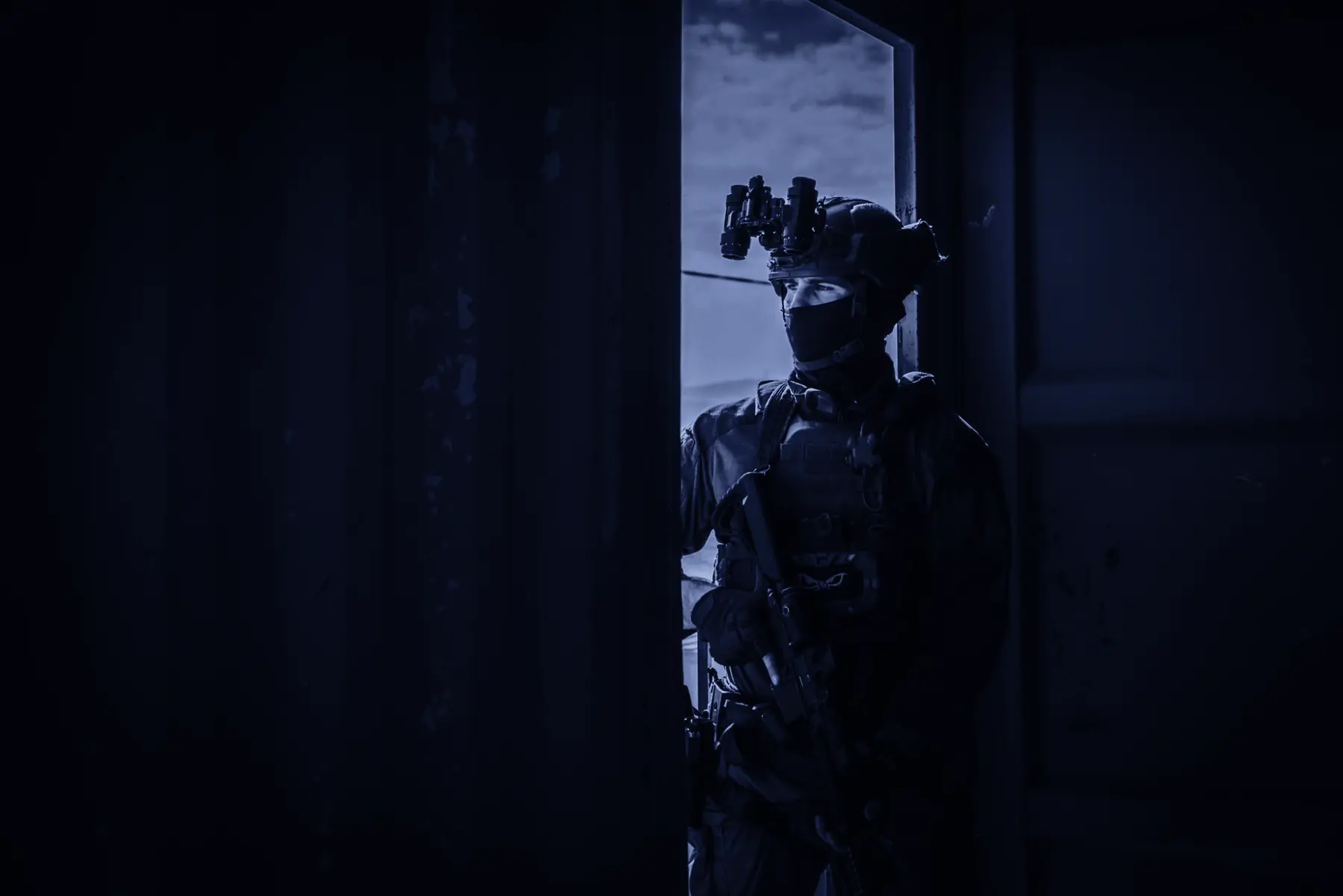 A Duvdevan soldier standing in a doorway, looking out.